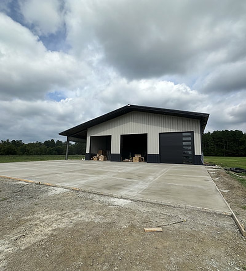 Finished concrete apron running out full width from the overhead doors of a new metal shop building
