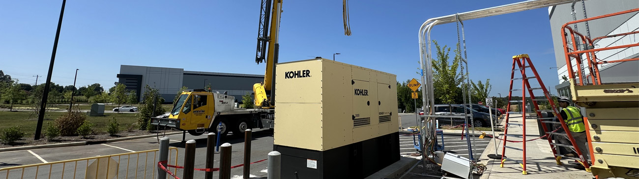 Standby generator set on a new concrete equipment pad protected by bollards at a commercial facility