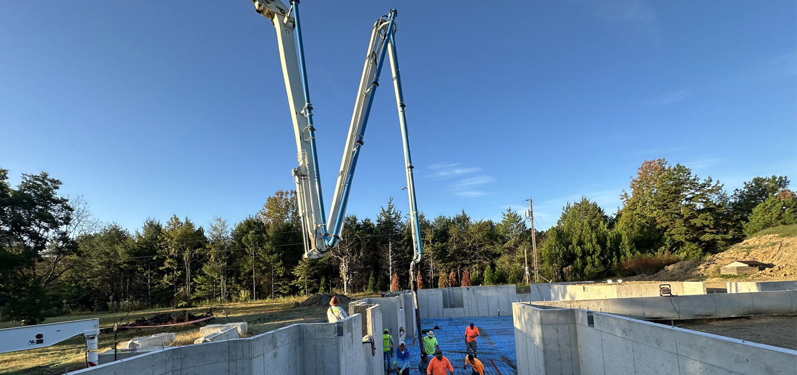Two boom pumps placing concrete into formed foundation walls