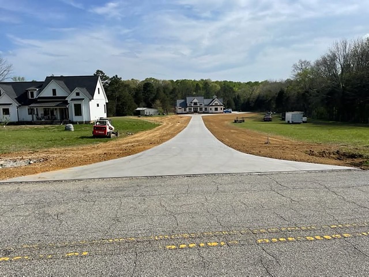 New residential concrete driveway running from the road up toward newly built houses