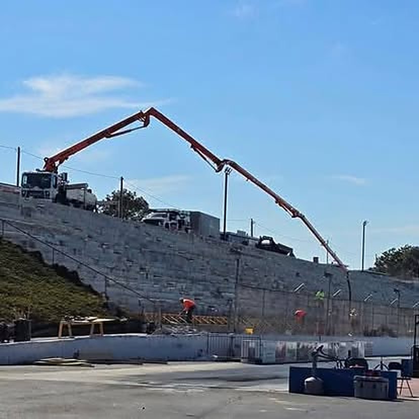 Tall stepped concrete retaining wall with a boom pump working from the grade above