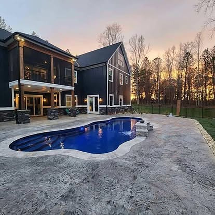 Stamped and colored concrete pool deck photographed at dusk